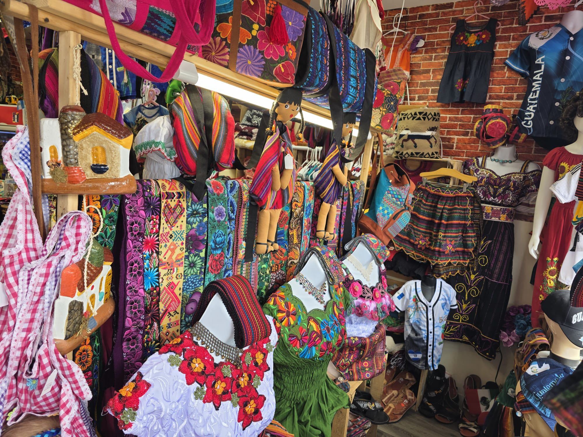 Vibrant display of traditional Guatemalan textiles, embroidered clothing, colorful bags, and authentic Central American crafts